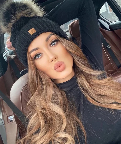 Cozy Blonde Waves Peeking From a Pom Pom Hat